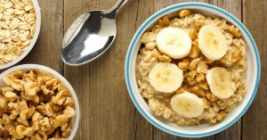 Banana walnut overnight oatmeal in a bowl on wood table, overhead view